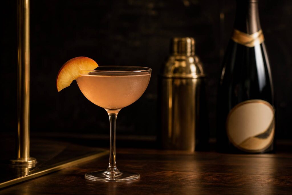 Verre de cocktail Bellini-Tini pêche sur un comptoir en bois sombre