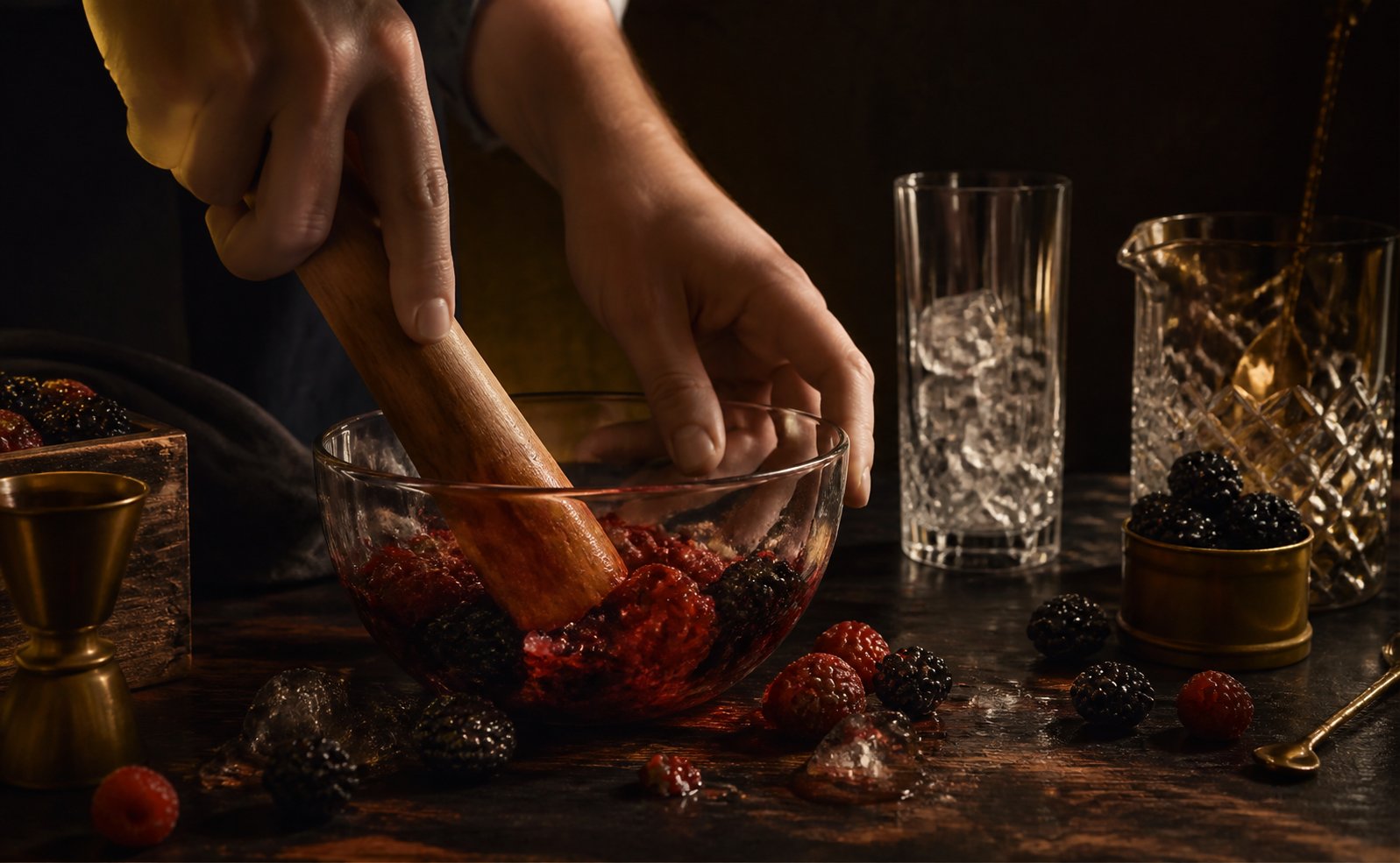 Mains écrasant des framboises et des mûres dans un bol en verre